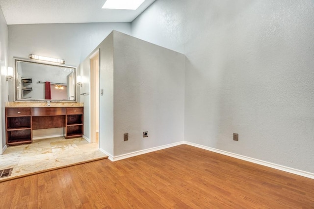 additional living space featuring vaulted ceiling with skylight, visible vents, baseboards, and wood finished floors