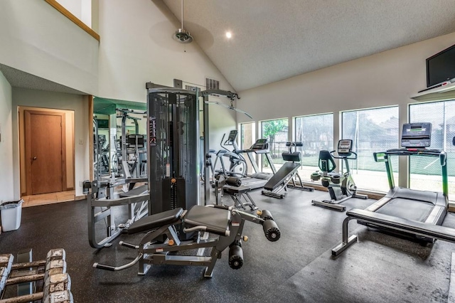 gym featuring a healthy amount of sunlight, a ceiling fan, high vaulted ceiling, and a textured ceiling