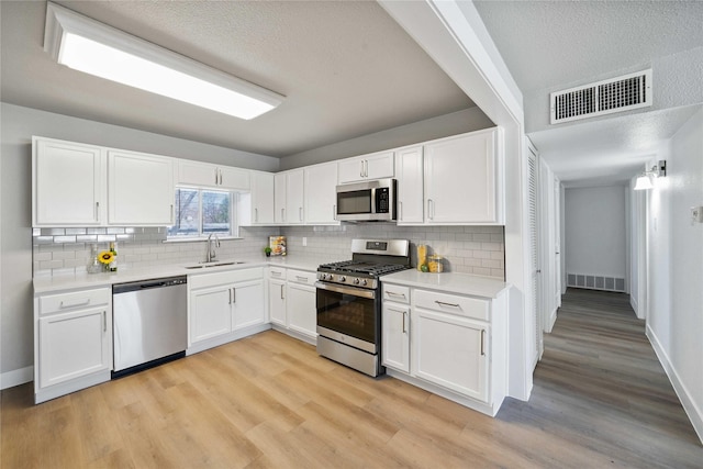 kitchen with visible vents, appliances with stainless steel finishes, light countertops, and a sink