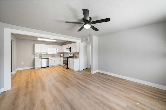 unfurnished living room featuring visible vents, baseboards, light wood-style flooring, ceiling fan, and a textured ceiling