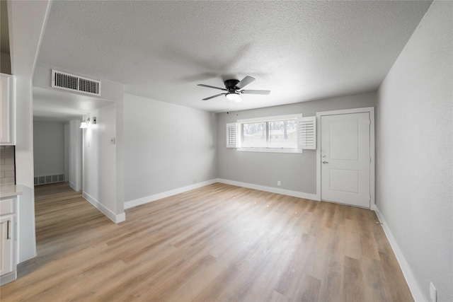 spare room featuring light wood-style flooring, visible vents, ceiling fan, and baseboards