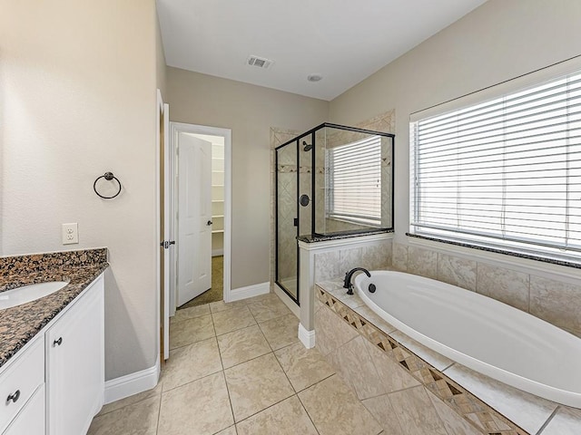 bathroom featuring visible vents, vanity, baseboards, a bath, and a stall shower