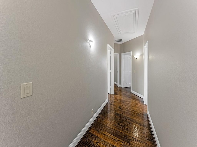 corridor featuring visible vents, wood finished floors, attic access, and baseboards