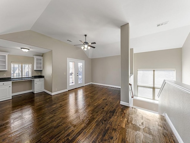 unfurnished living room with dark wood-style flooring, visible vents, vaulted ceiling, ceiling fan, and baseboards