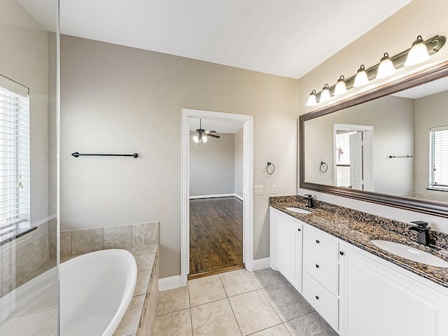 full bathroom featuring a garden tub, double vanity, tile patterned flooring, and a sink