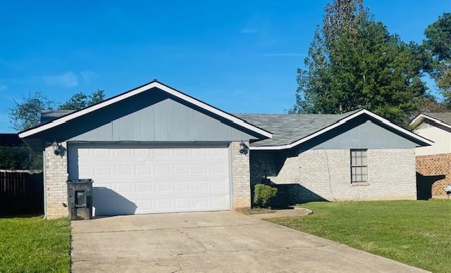 single story home featuring an attached garage, brick siding, driveway, and a front yard