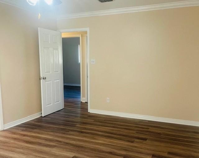 empty room featuring visible vents, baseboards, dark wood finished floors, and crown molding