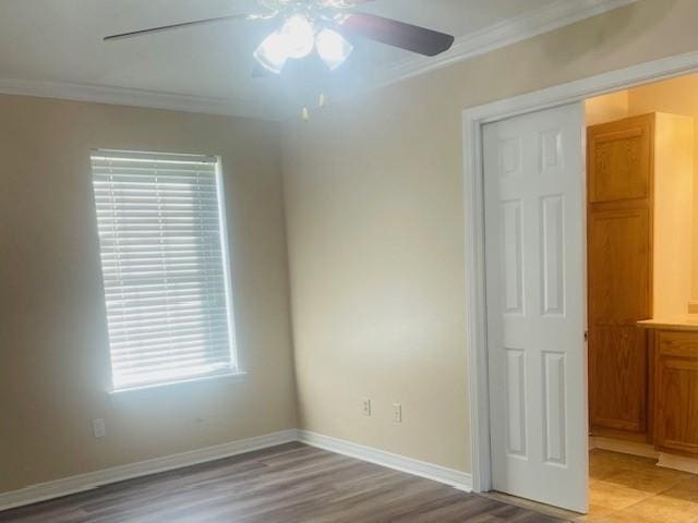 empty room featuring light wood-type flooring, baseboards, ornamental molding, and ceiling fan