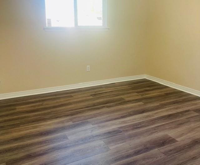 unfurnished room featuring dark wood-style flooring and baseboards