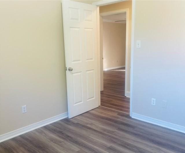 empty room with dark wood-style flooring and baseboards