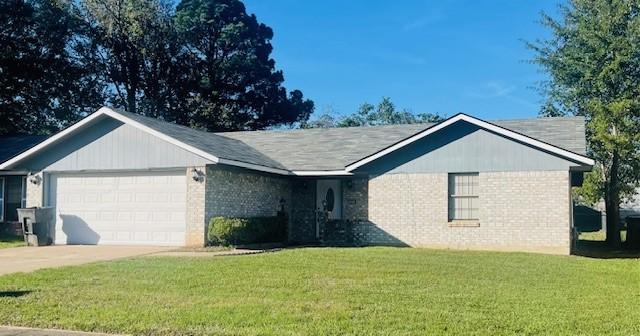 ranch-style home with a front yard, concrete driveway, brick siding, and an attached garage