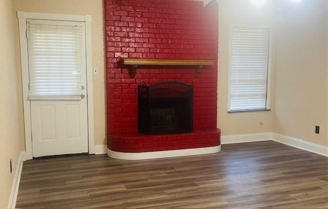 unfurnished living room featuring plenty of natural light, a fireplace, baseboards, and wood finished floors