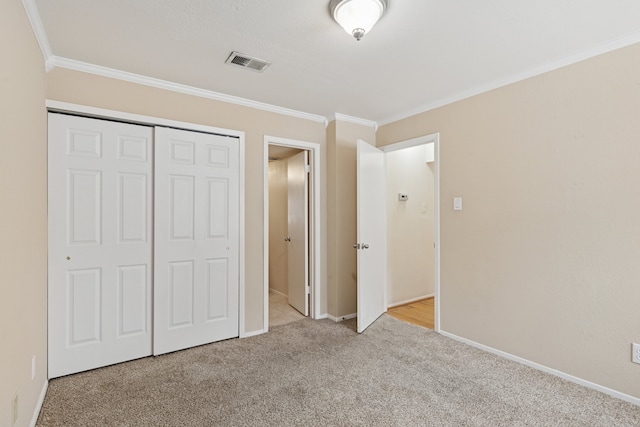 unfurnished bedroom with visible vents, baseboards, a closet, carpet, and crown molding