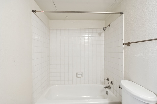 bathroom featuring shower / bath combination, toilet, and a textured wall