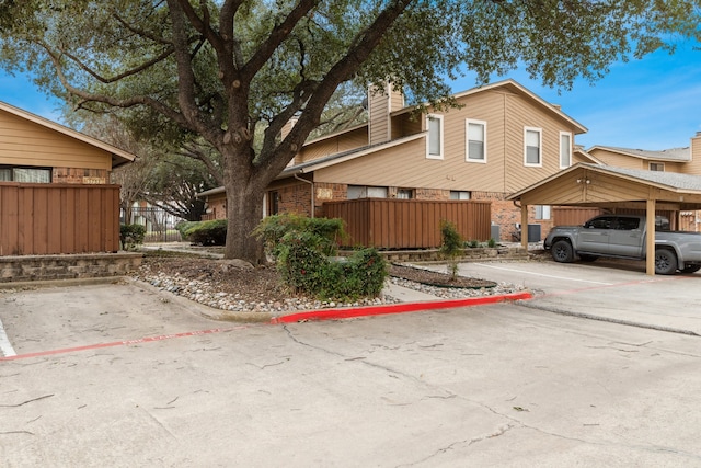 view of side of property featuring uncovered parking, brick siding, and fence