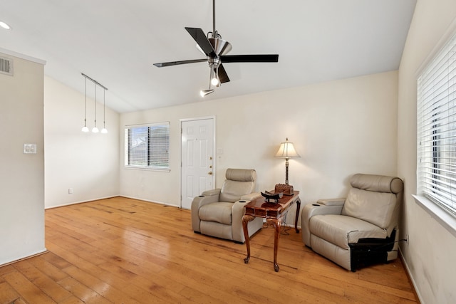 living area featuring lofted ceiling, light wood finished floors, a ceiling fan, and a wealth of natural light