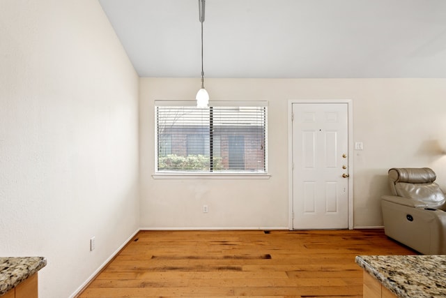 dining space featuring light wood-style floors, vaulted ceiling, and baseboards