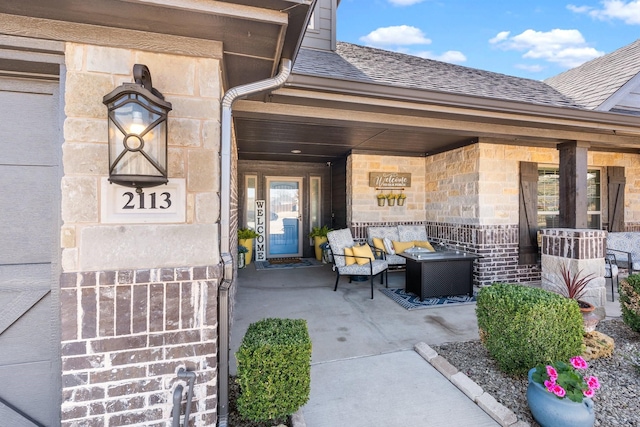 property entrance featuring stone siding, a shingled roof, and covered porch