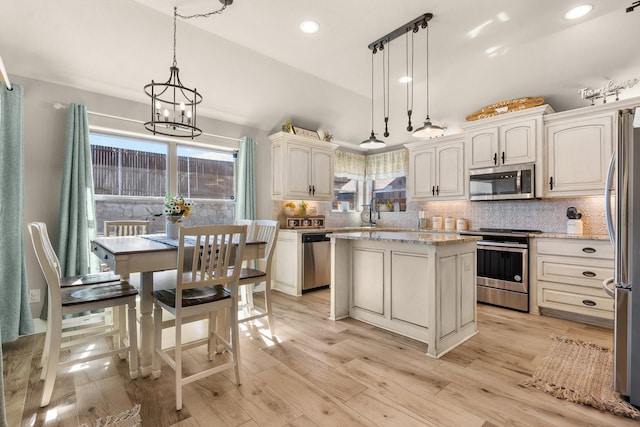 kitchen with light wood-style floors, stainless steel appliances, and backsplash