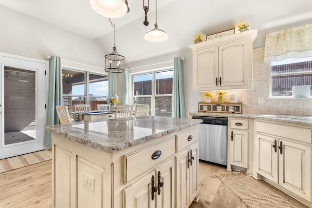 kitchen with cream cabinetry, lofted ceiling, decorative backsplash, stainless steel dishwasher, and light wood-style floors