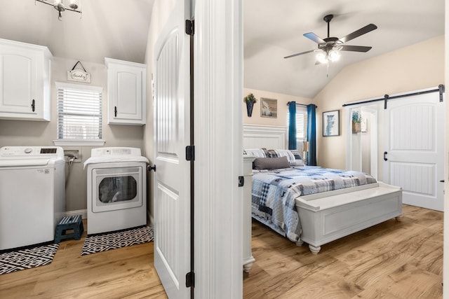 laundry area featuring a barn door, a ceiling fan, light wood-type flooring, cabinet space, and washing machine and clothes dryer