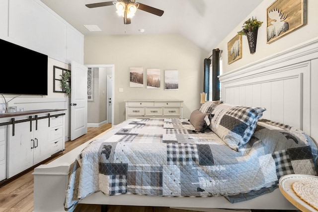 bedroom with light wood-style floors, vaulted ceiling, and a ceiling fan