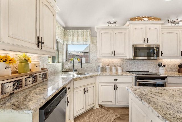 kitchen featuring stainless steel appliances, tasteful backsplash, a sink, and light stone counters