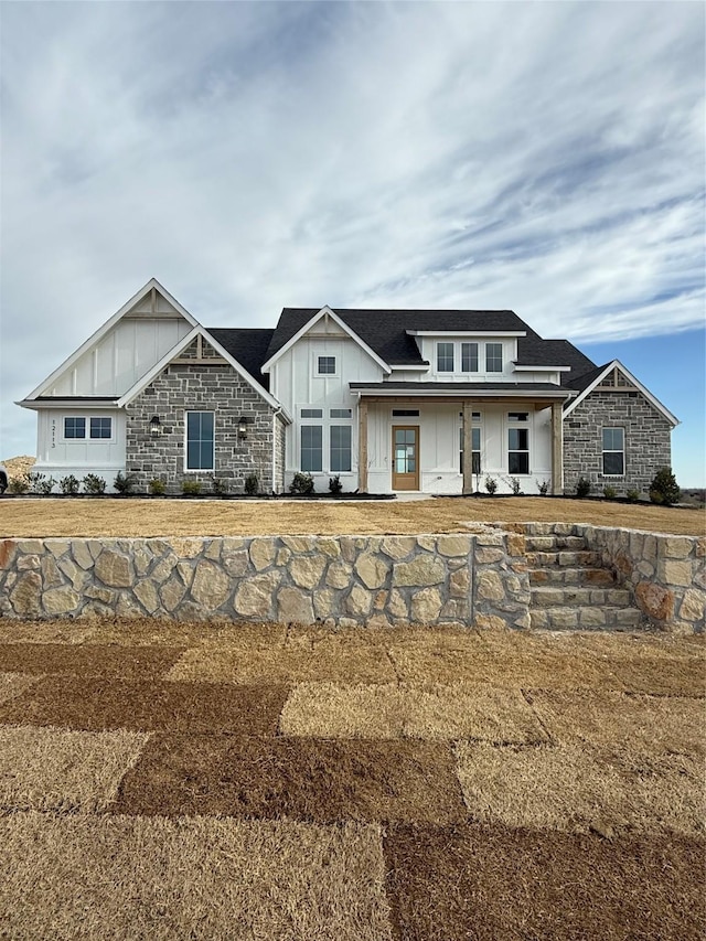 view of front facade with board and batten siding, stone siding, and a porch