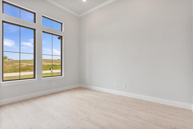 spare room with light wood-style floors, ornamental molding, and baseboards