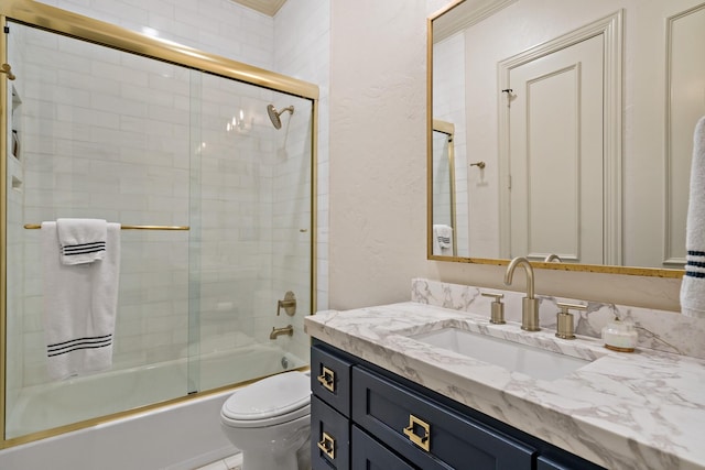 bathroom featuring vanity, toilet, and bath / shower combo with glass door