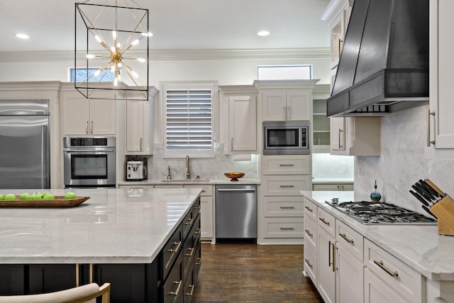 kitchen featuring wall chimney exhaust hood, crown molding, a sink, and built in appliances