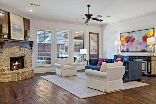 living room featuring a stone fireplace, visible vents, dark wood-style flooring, and ornamental molding