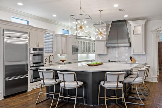 kitchen featuring built in appliances, a sink, visible vents, ornamental molding, and custom exhaust hood