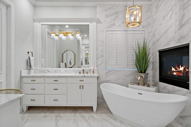 full bath with a premium fireplace, ornamental molding, marble finish floor, vanity, and a freestanding tub