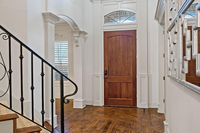 foyer entrance featuring stairway, baseboards, dark wood-style floors, and arched walkways