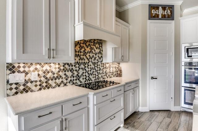 kitchen with tasteful backsplash, appliances with stainless steel finishes, light countertops, and ornamental molding