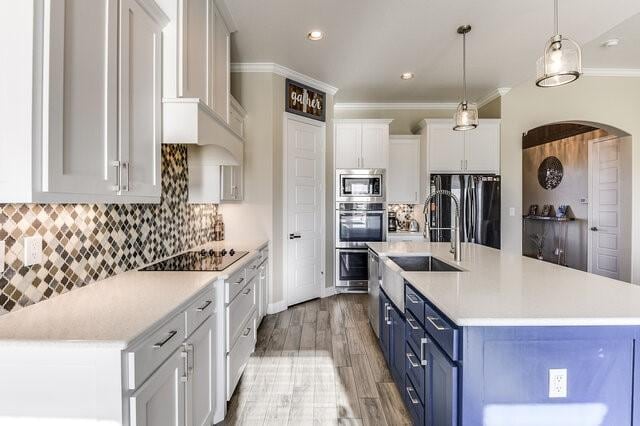 kitchen featuring crown molding, stainless steel appliances, light countertops, and blue cabinets