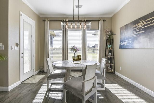 dining room featuring plenty of natural light, visible vents, dark wood finished floors, and ornamental molding