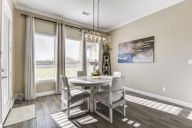 dining room with crown molding, baseboards, and wood finished floors