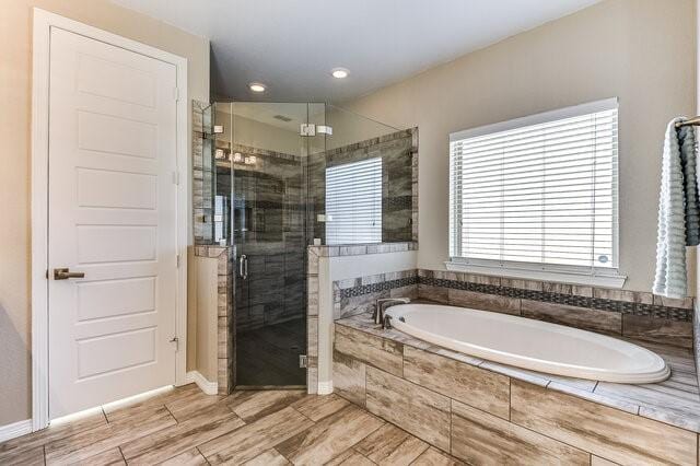 bathroom featuring a stall shower, wood tiled floor, and a bath