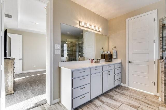 bathroom featuring tiled shower, vanity, visible vents, and wood tiled floor