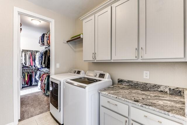 clothes washing area featuring light tile patterned floors, light carpet, cabinet space, and separate washer and dryer