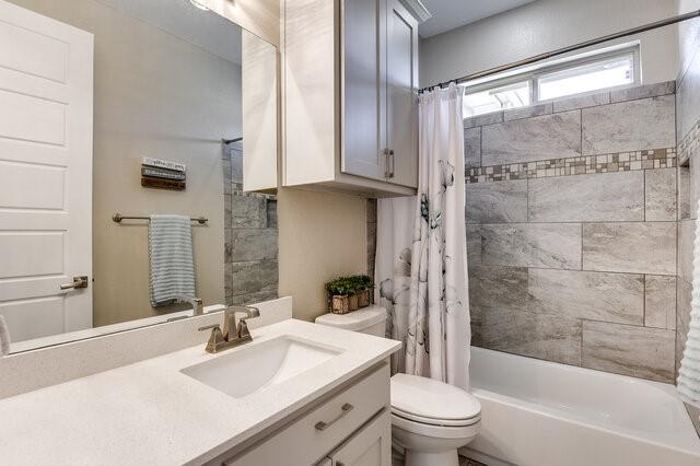 full bathroom featuring toilet, shower / tub combo with curtain, and vanity