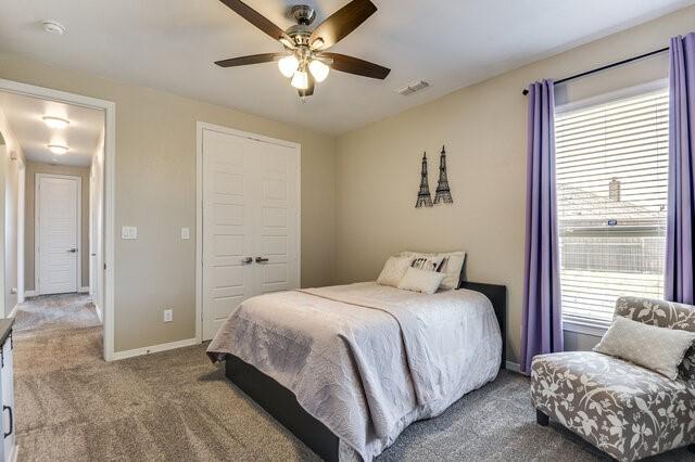 carpeted bedroom featuring baseboards, multiple windows, visible vents, and a closet