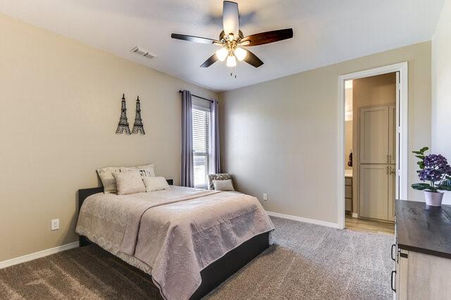 bedroom featuring a ceiling fan, light colored carpet, visible vents, and baseboards