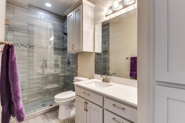 bathroom with toilet, a shower stall, and vanity