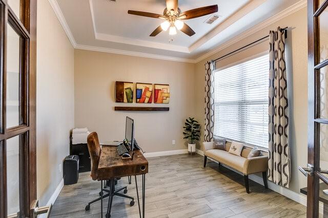 office area with crown molding, visible vents, a raised ceiling, and wood finished floors