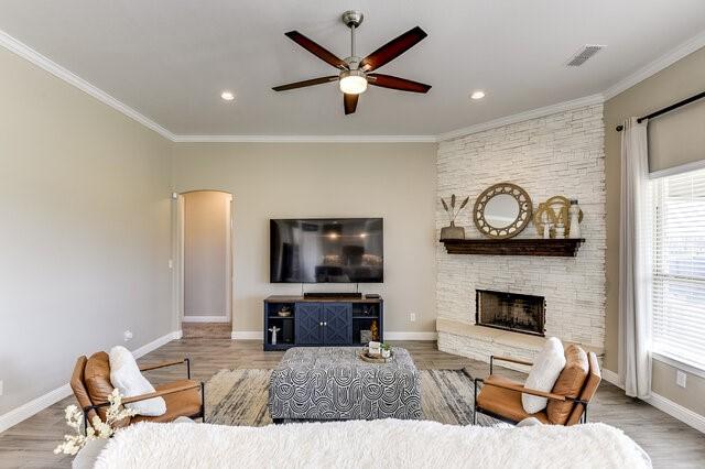 living area with arched walkways, visible vents, and crown molding