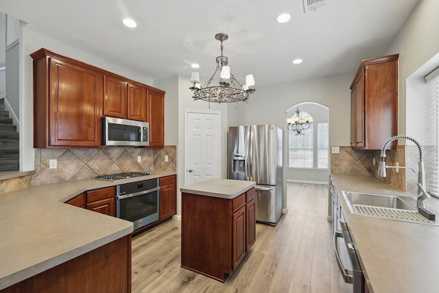 kitchen with light wood finished floors, tasteful backsplash, appliances with stainless steel finishes, a sink, and a notable chandelier