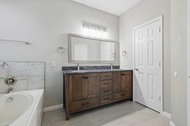 bathroom with double vanity, a tub to relax in, baseboards, and a sink